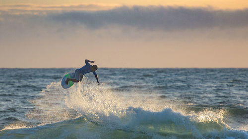 People surfing in sea at sunset