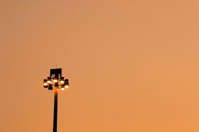 Low angle view of illuminated street light against orange sky