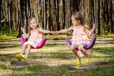 Sisters swinging against trees