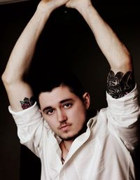 Portrait of young man with arms raised standing against black background