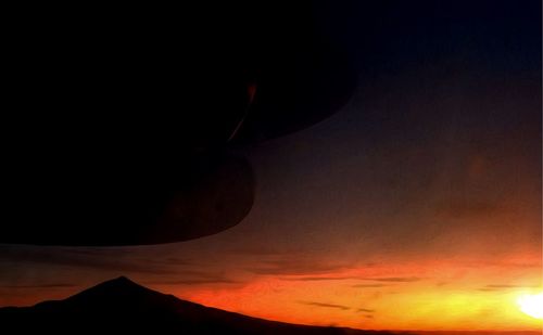 Scenic view of silhouette mountain against orange sky
