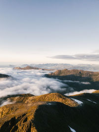 Scenic view of mountains among clouds against sky