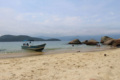 Boat moored on beach against sky