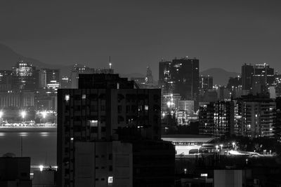 Illuminated buildings in city against clear sky at night