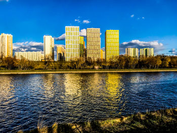 River by buildings against blue sky