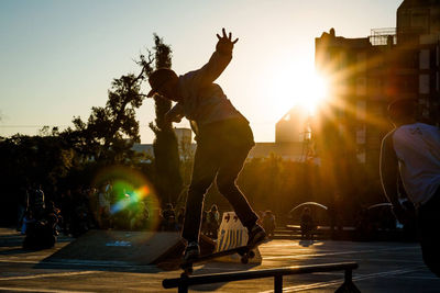 People looking at man skateboarding during sunset in city