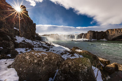 Scenic view of river by mountains against sky at winter