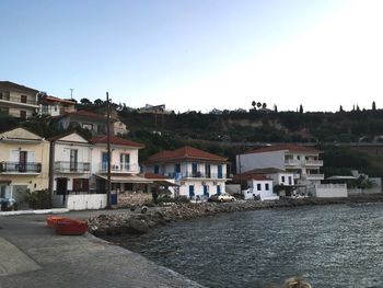 Houses by river in town against clear sky