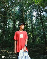 Portrait of man standing against trees in forest