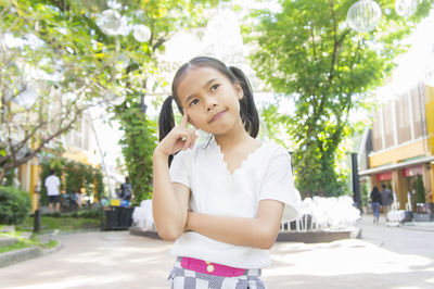 Thoughtful girl looking away while standing at public park