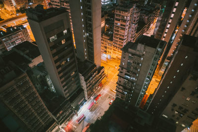 High angle view of illuminated street amidst buildings in city at night