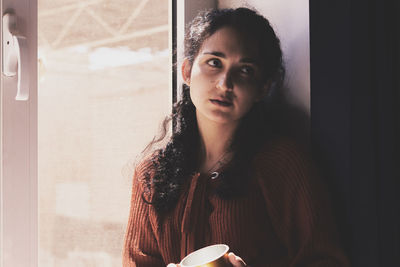 Woman looking away while sitting by window