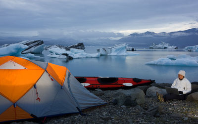 Woman using her laptop at campsite by glacier lagoon