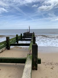 Wooden posts on beach against sky