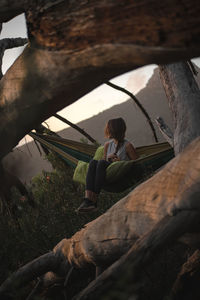 Woman sitting on wooden log