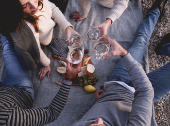 High angle view of people toasting drinks while sitting outdoors