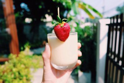 Cropped hand of person holding strawberry smoothie