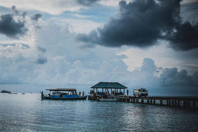 Pier on sea against cloudy sky