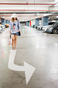 Full length of woman standing at parking lot