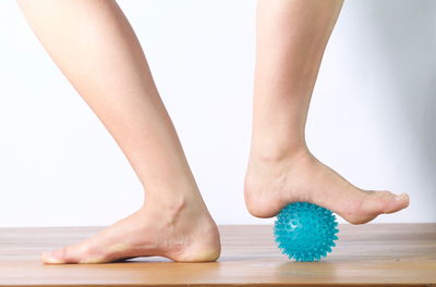 Low section of woman standing on rubber ball indoors