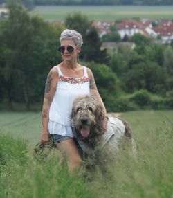 Woman with dog standing amidst grassy field