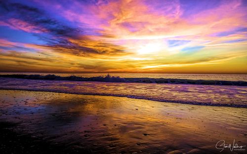 Scenic view of sea against dramatic sky during sunset