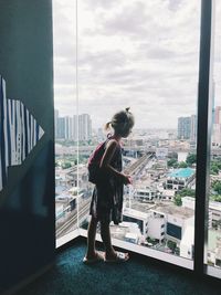 Girl looking through window in city