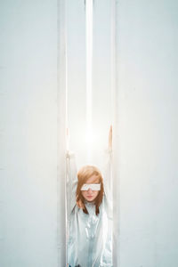 Portrait of young woman against white wall