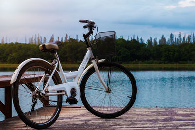 Bicycle by lake against sky