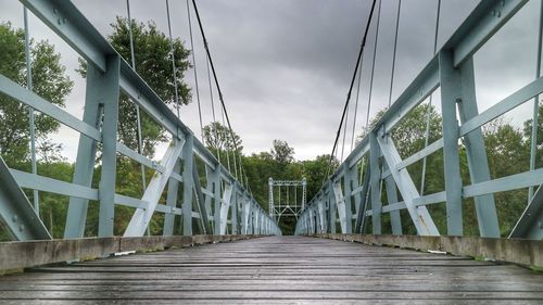 Footbridge amidst trees against sky