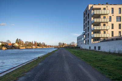 Road by buildings against sky in city