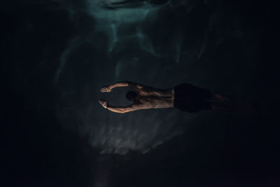 Overhead view of shirtless man swimming in water during night