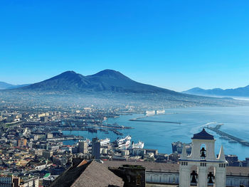 High angle view of townscape and mountains against clear blue sky