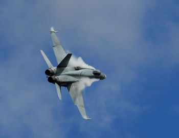 Low angle view of fighter plane flying against cloudy sky