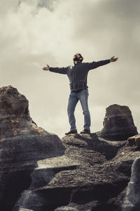 Rear view of man standing on rock against sky