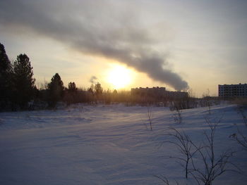Scenic view of snow covered field against sky at sunset