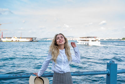 Portrait of smiling young woman in sea against sky