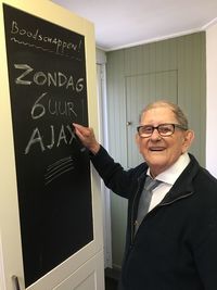 Portrait of man standing by text on blackboard