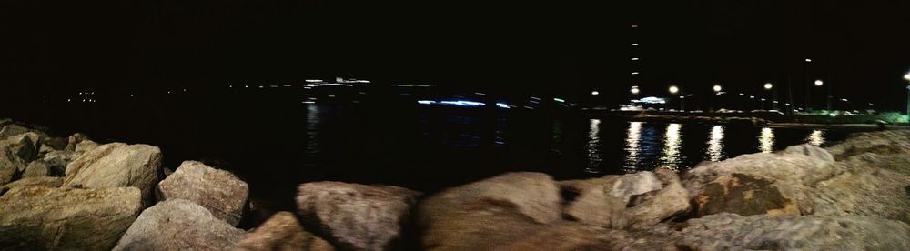 Illuminated bridge over river against sky at night