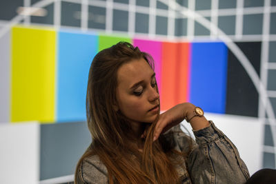 Close-up of young woman against multi colored wall