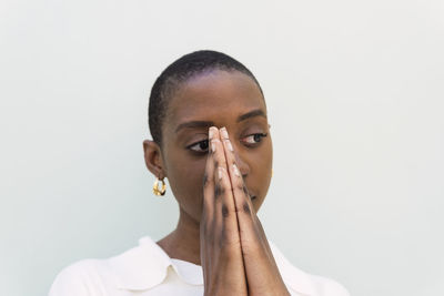 Young woman with hands clasped against white background