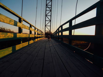 Bridge walking on footbridge against sky during sunset