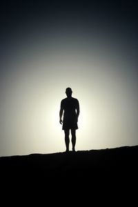 Silhouette man standing on field against sky during sunset