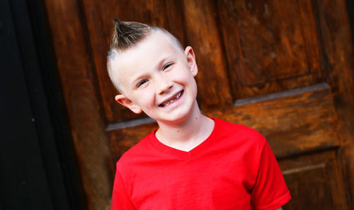 Portrait of smiling boy standing against door