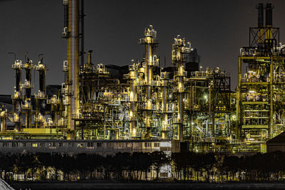 Illuminated factory against sky at night