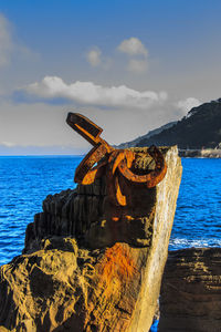 Rock on beach against sky