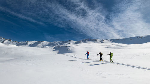 Three friends during a ski mountaineering trip on the trail.