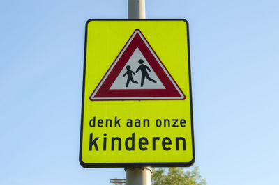 Close-up of road sign against clear blue sky