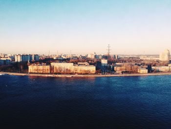 River by cityscape against clear sky