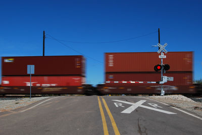 Train passing by railroad crossing against clear blue sky